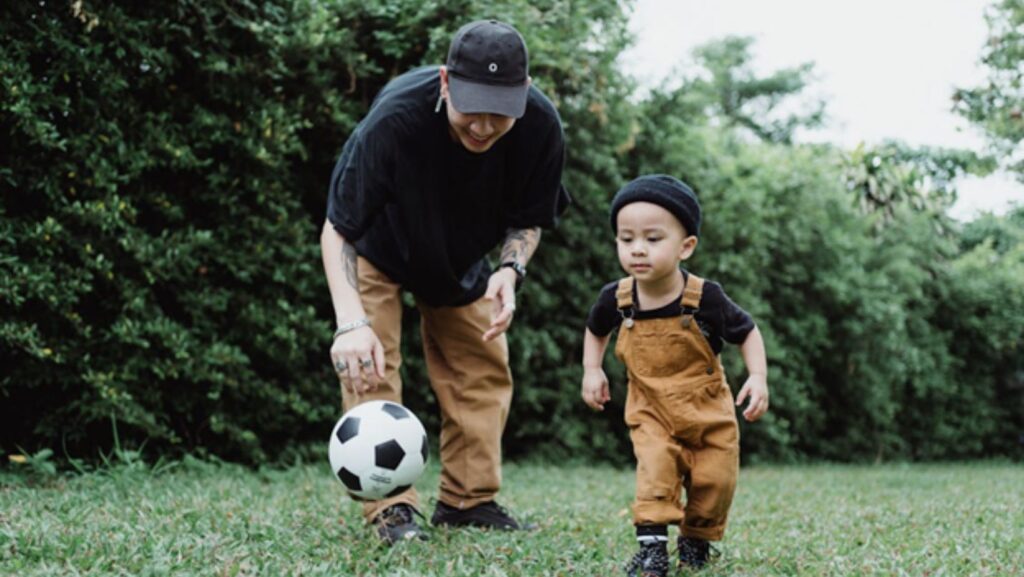 father teaching son to play soccer